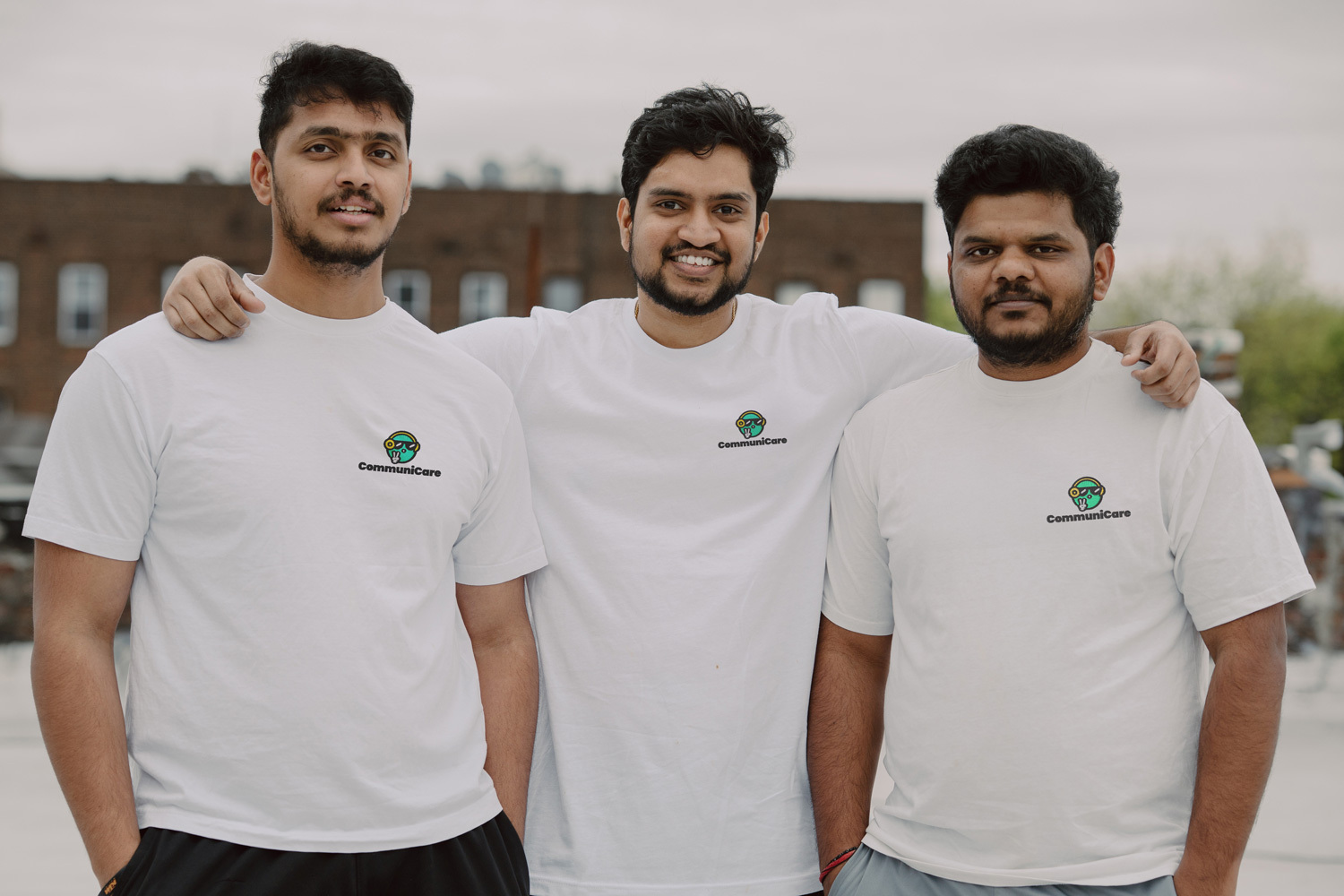 Three men wear Communicare tshirts and smile for the camera