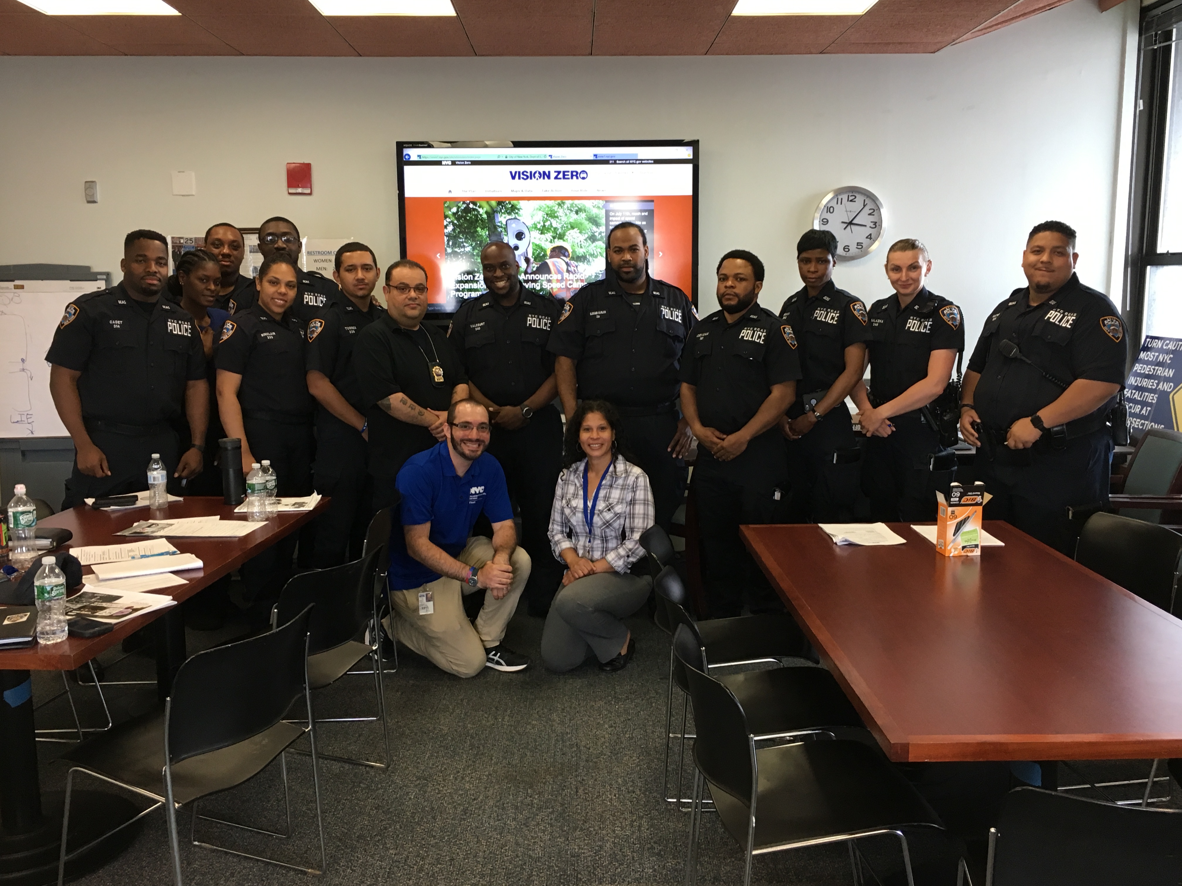 Nathaniel Koszer, with police officers after a work presentation. He is in the front row kneeling in a blue shirt.